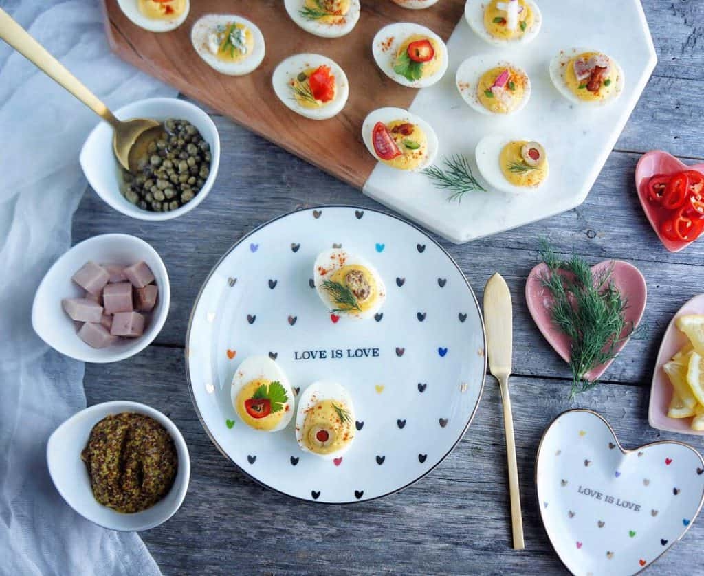 Deviled eggs on a platter and plates with toppings