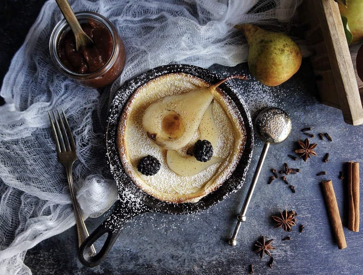 dutch baby pancake with poached pear and powdered sugar