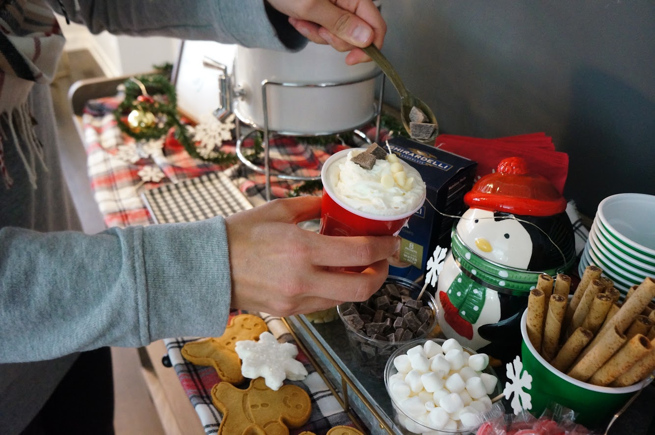 someone topping their hot cocoa at the hot cocoa bar