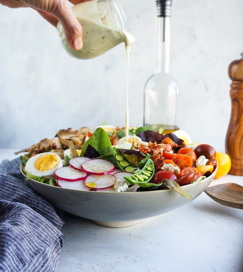 pouring Avocado Vinaigrette on Cobb Salad 