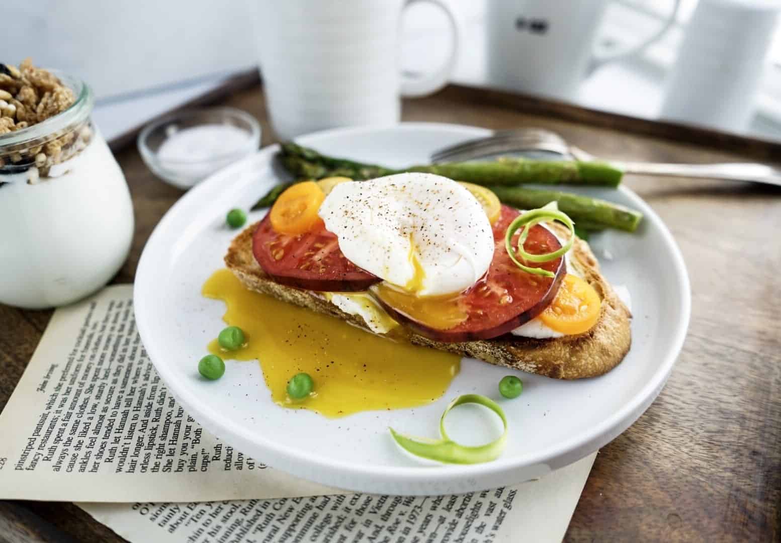 yolk punctured on tomato toast with poached egg