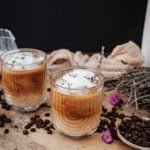 iced lavender latte in glass mug with dried lavender sprig garnish