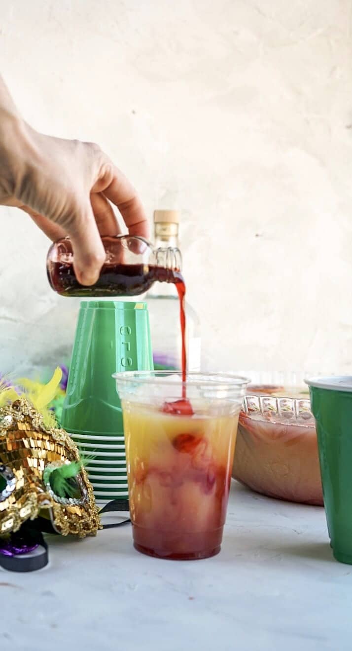 pouring blood orange syrup in cup of Hurricane Punch