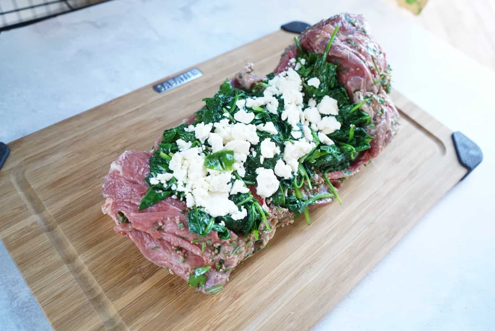 raw leg of lamb with spinach and feta stuffing before rolling