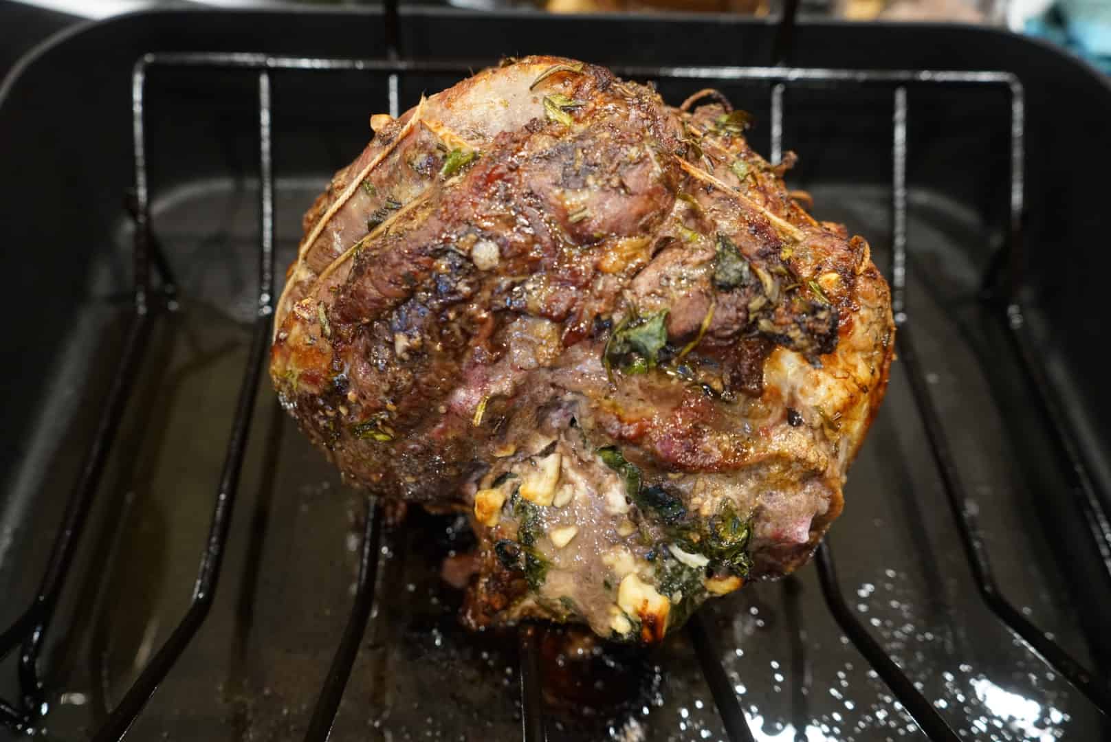 roasted stuffed leg of lamb on roasting rack in roasting pan