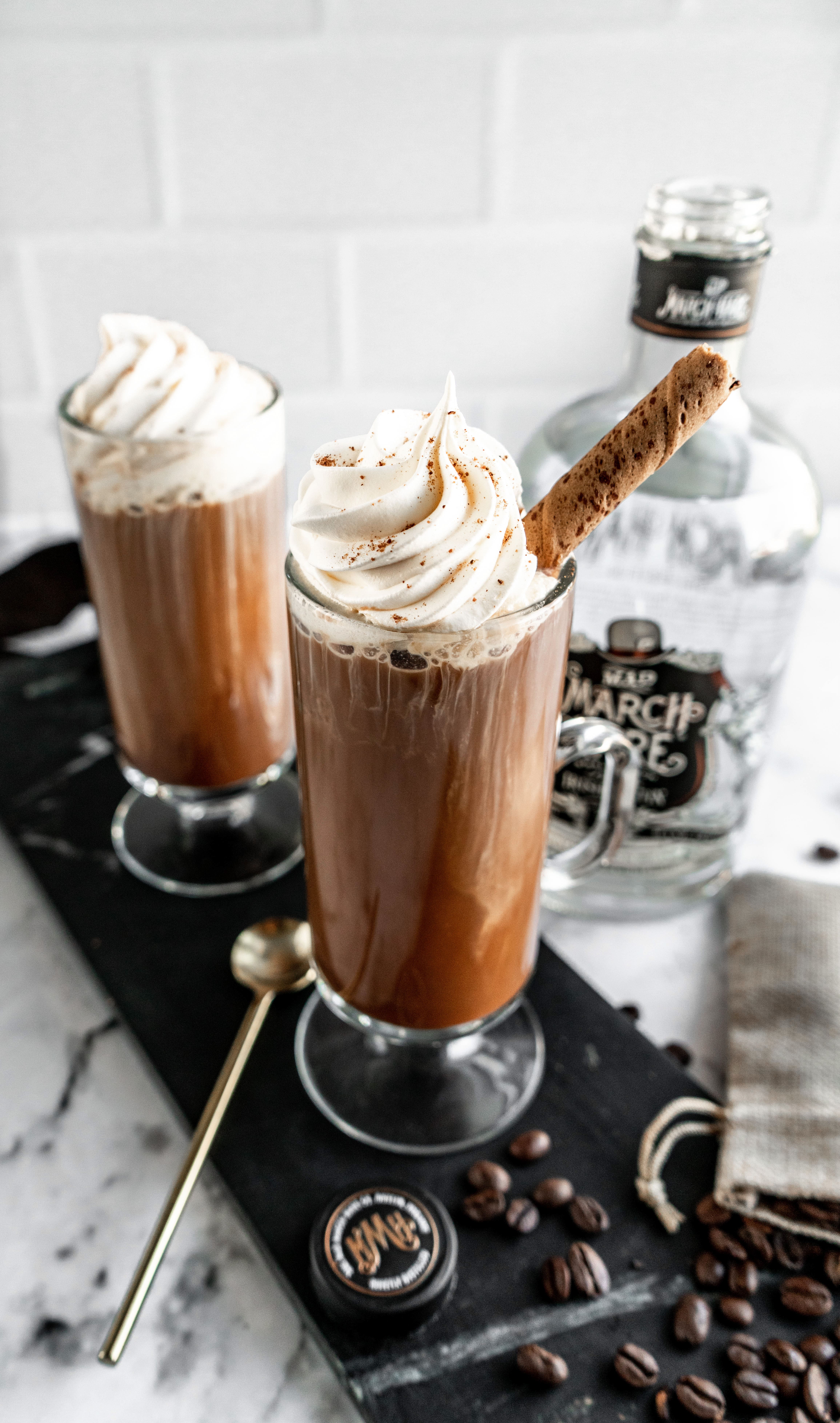 irish coffee garnished with whipped cream on black tray 