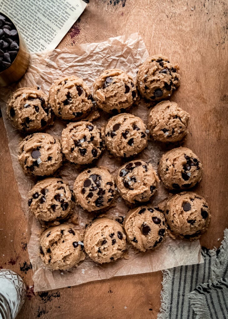 overhead shot of chocolate chip cookie dough rounds on parchment paper 