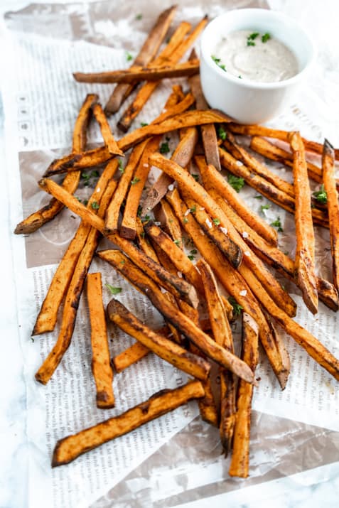 air fryer sweet potato fries cooked on parchment paper with dipping sauce
