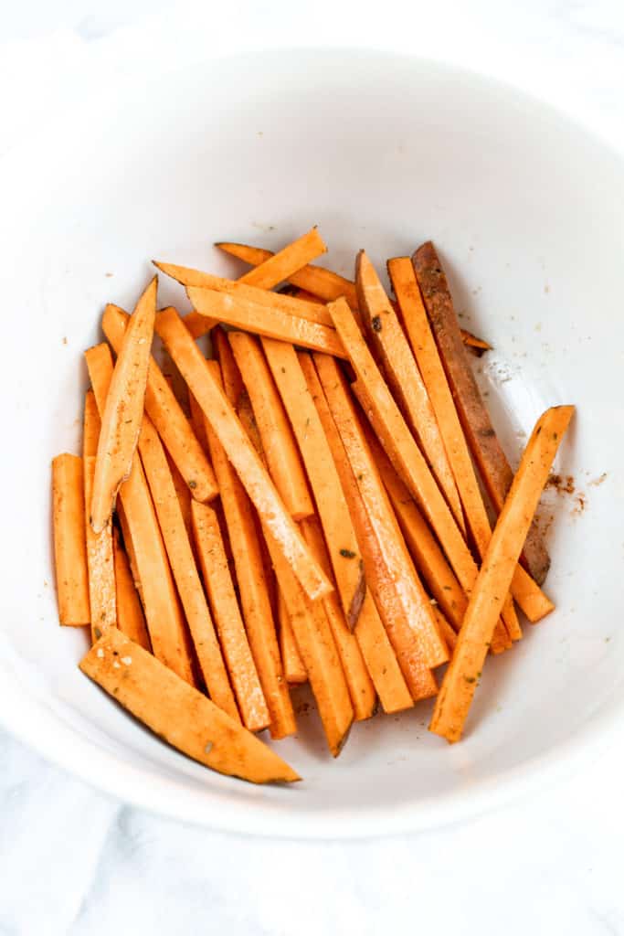 sweet potato fries before cooking in bowl with seasoning