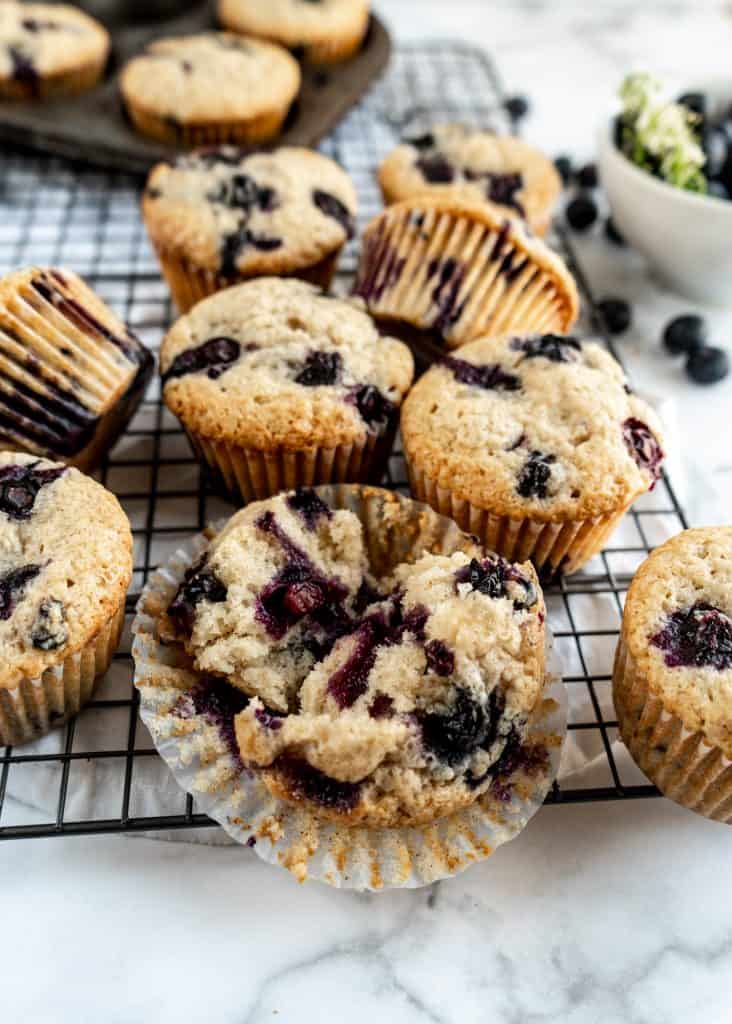 bakery style blueberry muffins close up on cooling rack, one muffin cut in half