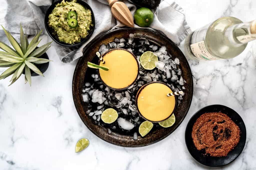 mango ginger margarita on drink tray with limes