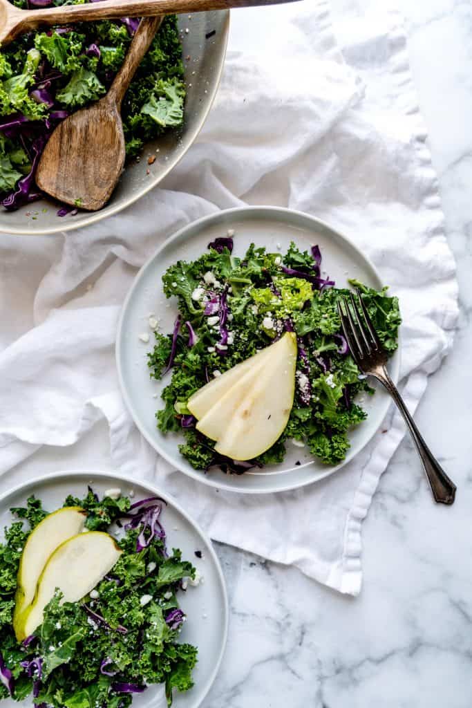 kale salad plated with sliced pear