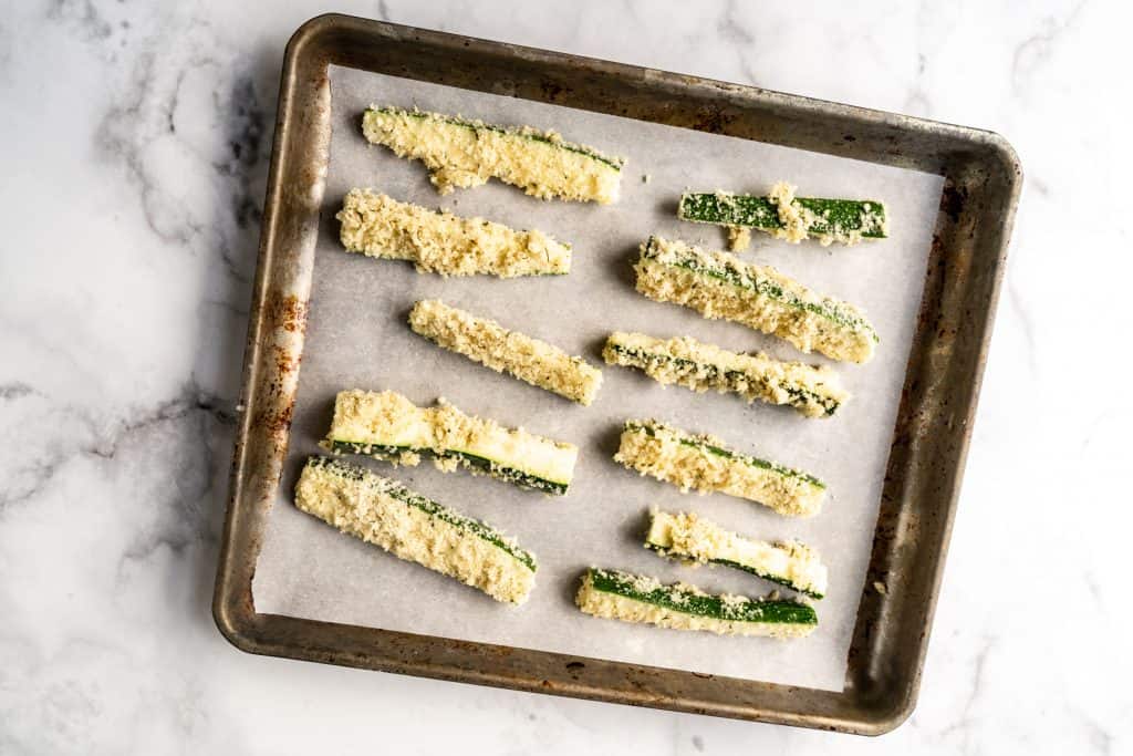 raw zucchini fries on baking sheet