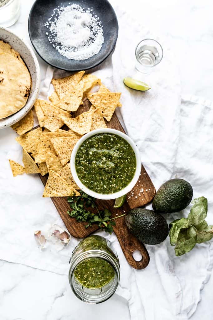 roasted salsa verde in bowl with chips on cutting board