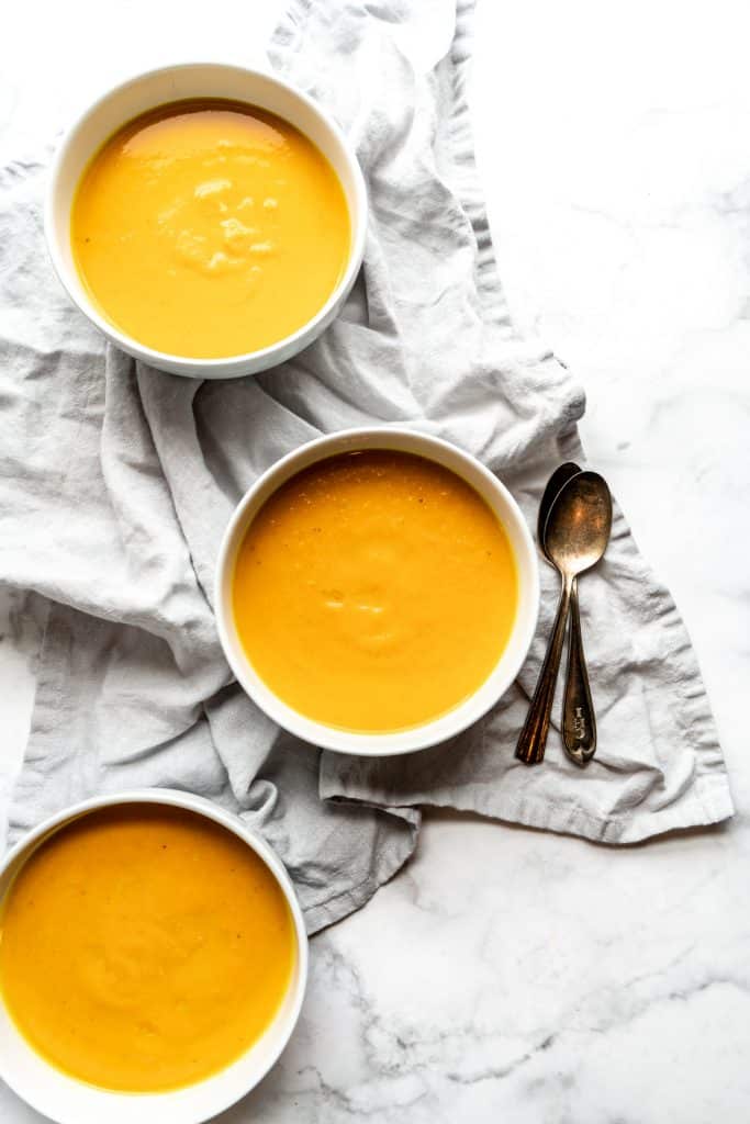 carrot apple soup in three bowls without garnish