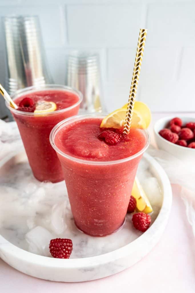 raspberry Frosé in clear solo cup with straw and fresh raspberries