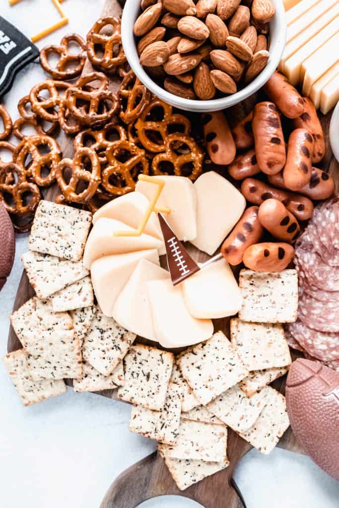 football charcuterie board close up with crackers and smoked gouda and lit'l smokies