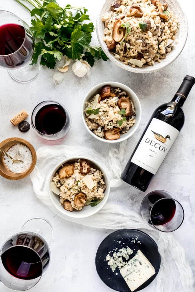 Instant pot Mushroom Gorgonzola risotto in bowls in flatlay with red wine in glasses
