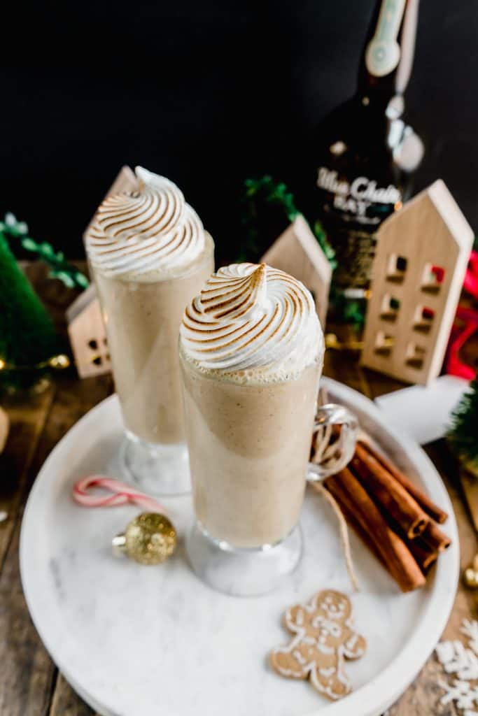 gingerbread coquito on marble serving tray with gingerbread cookies and cinnamon sticks