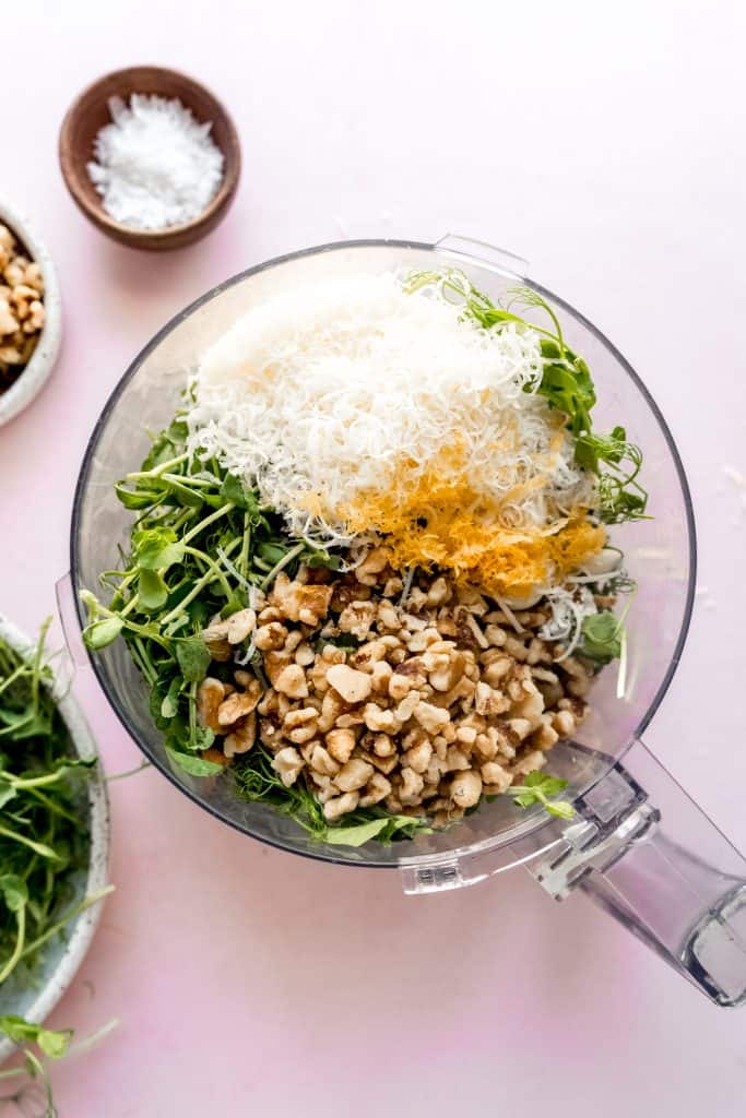 top down shot of pea shoot pesto ingredients in food processor 