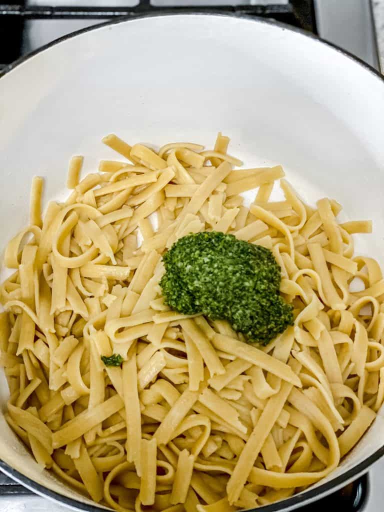 cooked fettuccine in stock pot with spoonful of pesto