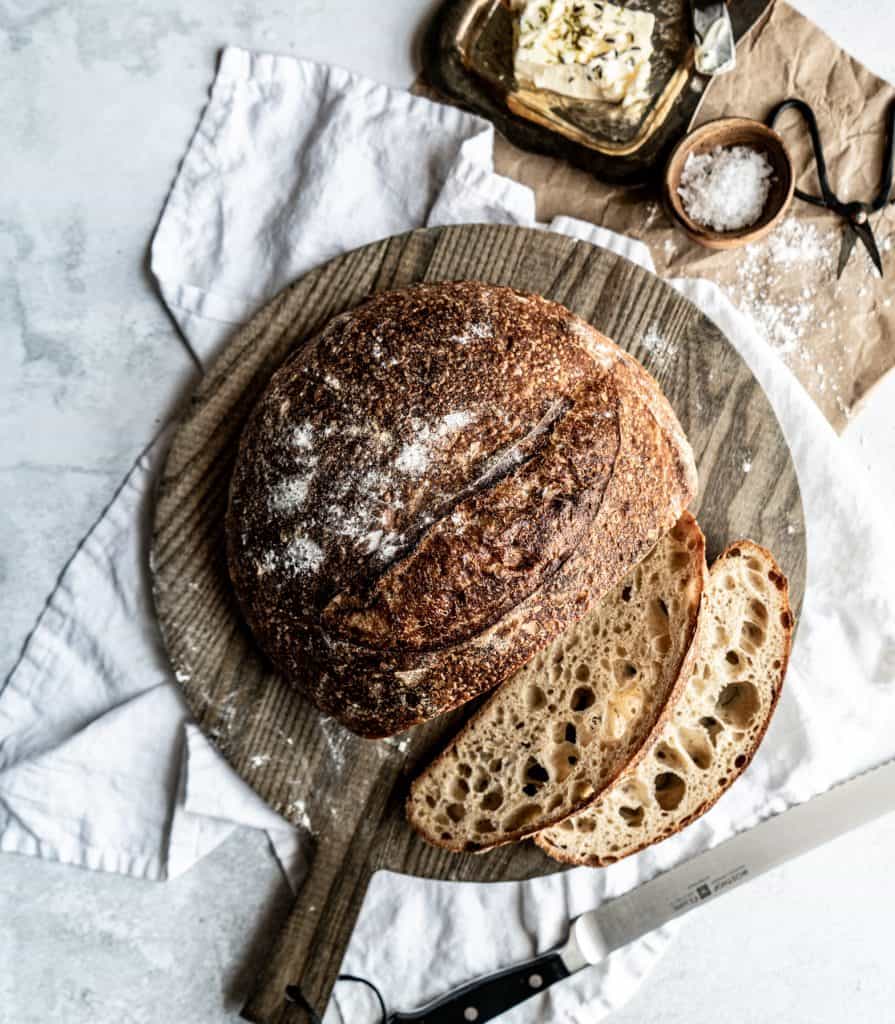 sourdough loaf on cutting board with two slices cut 