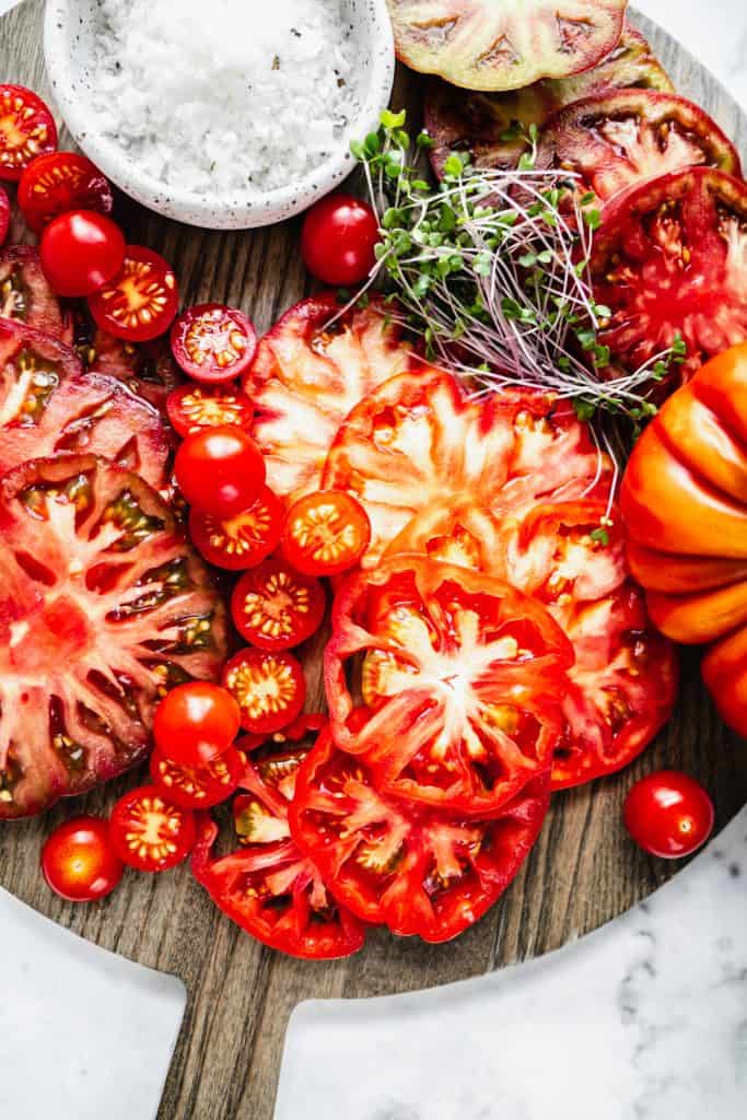 heirloom tomatoes and grape tomatoes sliced on cutting board 