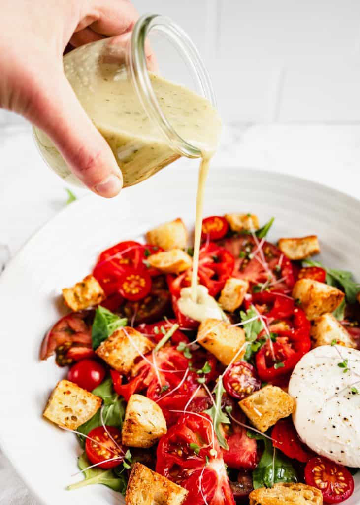 basil vinaigrette poured on panzanella salad