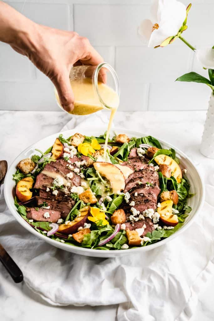 salad dressing being poured on salad