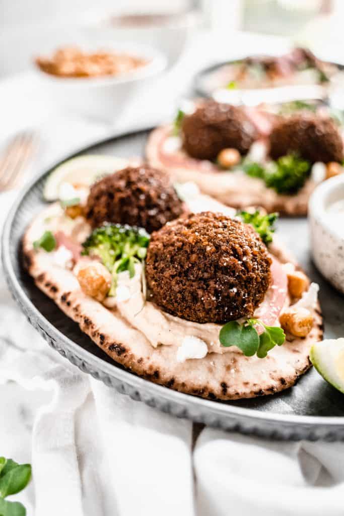 close up shot of sweet potato falafel on pita with toppings on plate