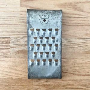 Metal vintage cheese grater on a wood background