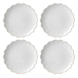 Four white plates with a scalloped edge on a white background