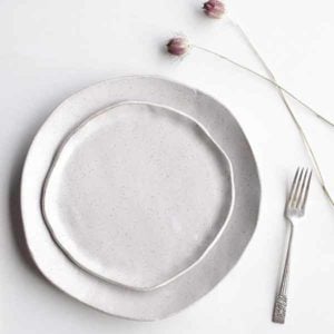 Top view of two white plates with a fork and flowers beside them