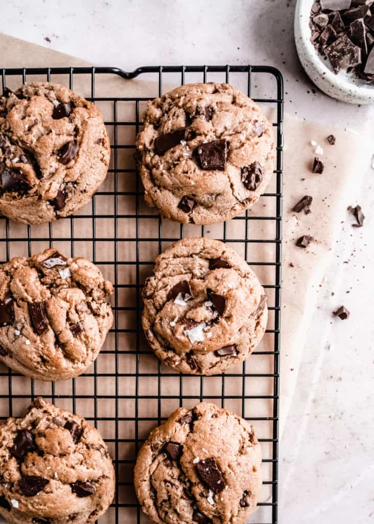 brown butter toffee chocolate chunk cookies baked on cooling rack, bowl of chopped chocolate on the side 