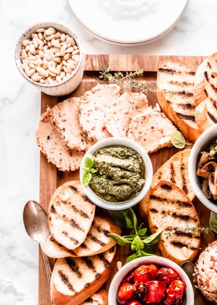 close up of pesto, on board in bowls with grilled bread surrounding 