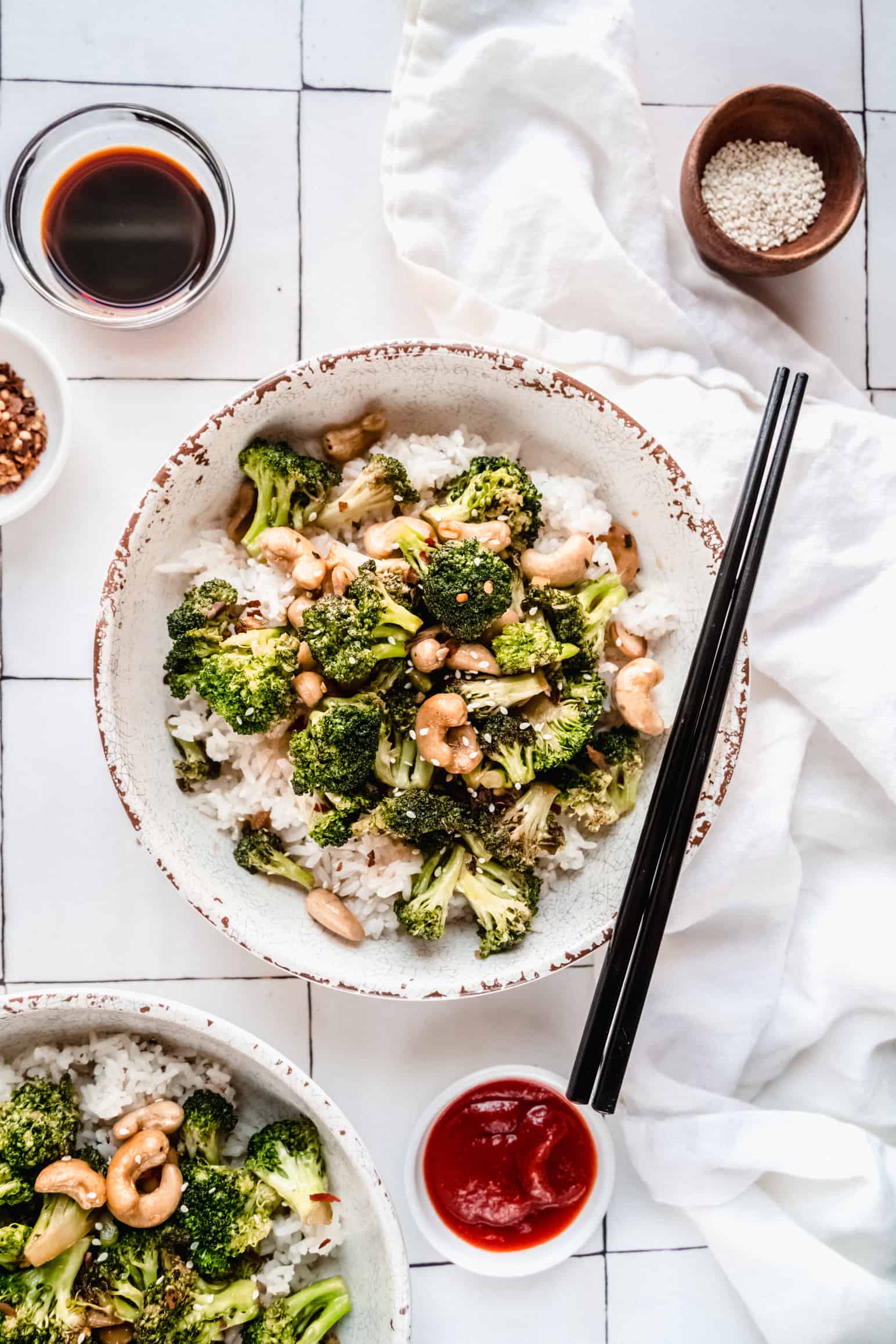 broccoli cashew stir fry in a bowl over white rice with chopsticks placed on top of bowl.