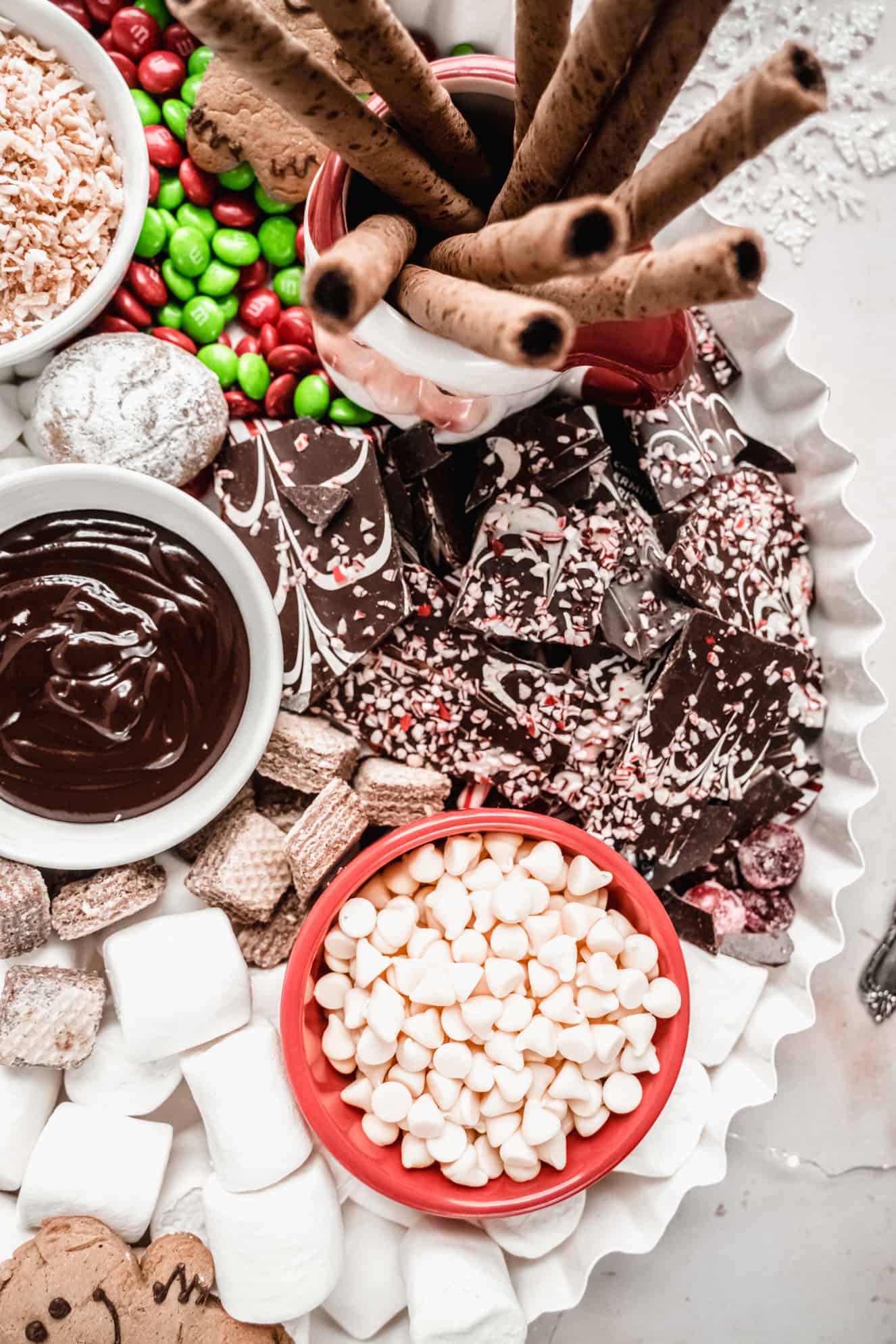 close up of peppermint bark, chocolate sauce, white chocolate chips on hot chocolate charcuterie board