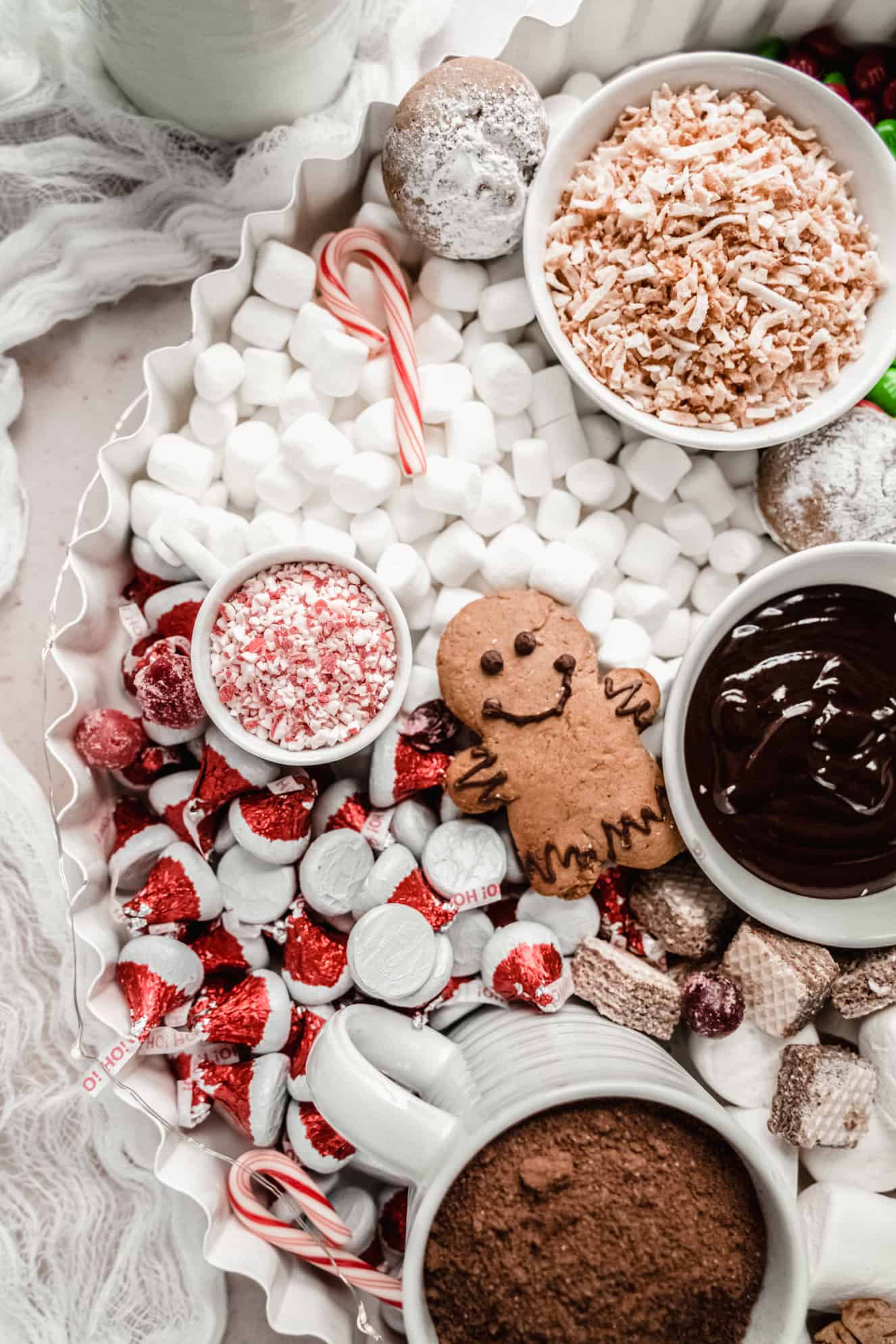 close up of hershey kisses; mini marshmallows and crushed candy cane pieces on hot chocolate charcuterie board