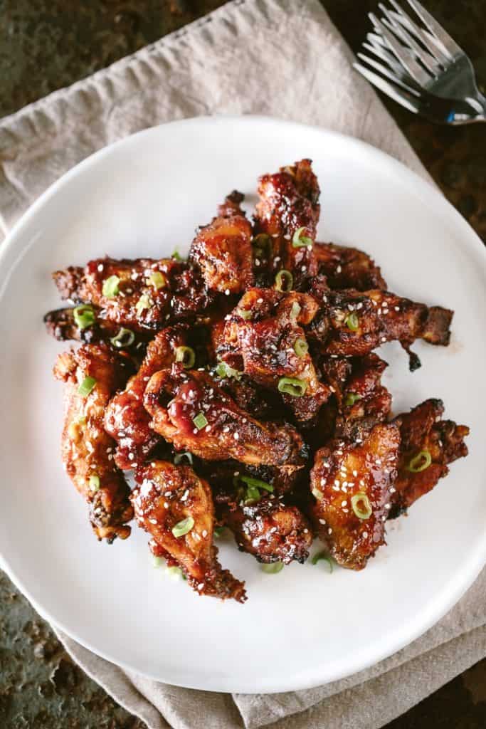 baked chicken wings garnished with green onion and sesame seeds on plate 