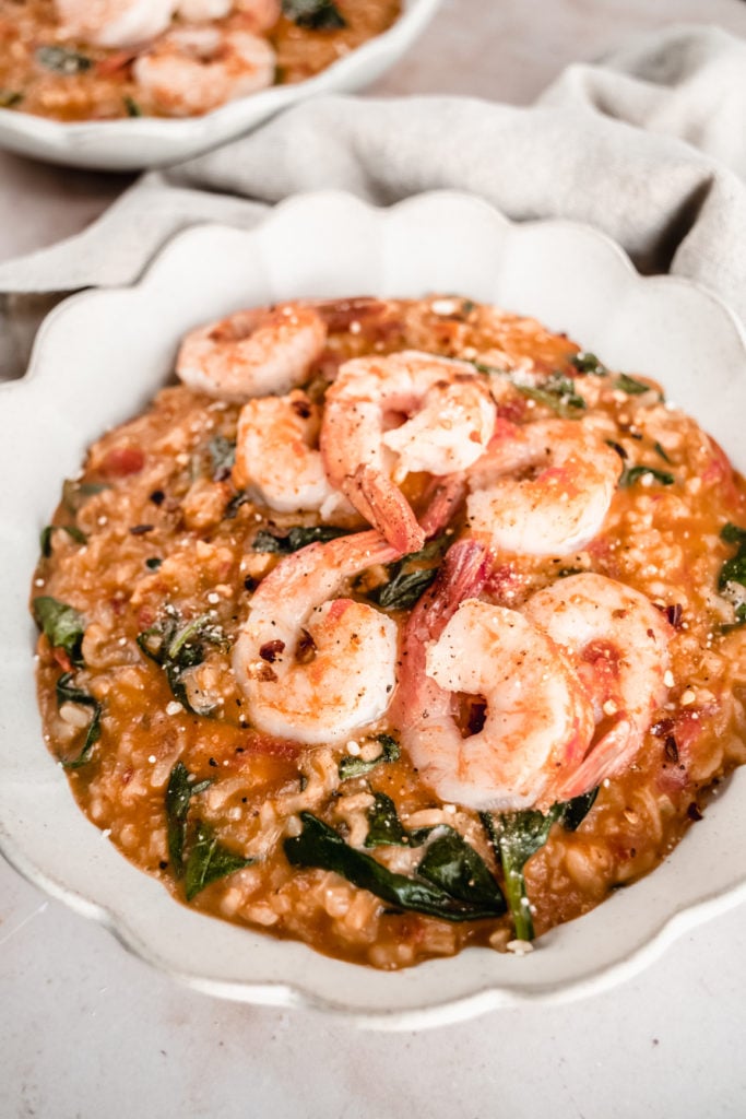 close up shot of shrimp tomato risotto in a scalloped bowl 