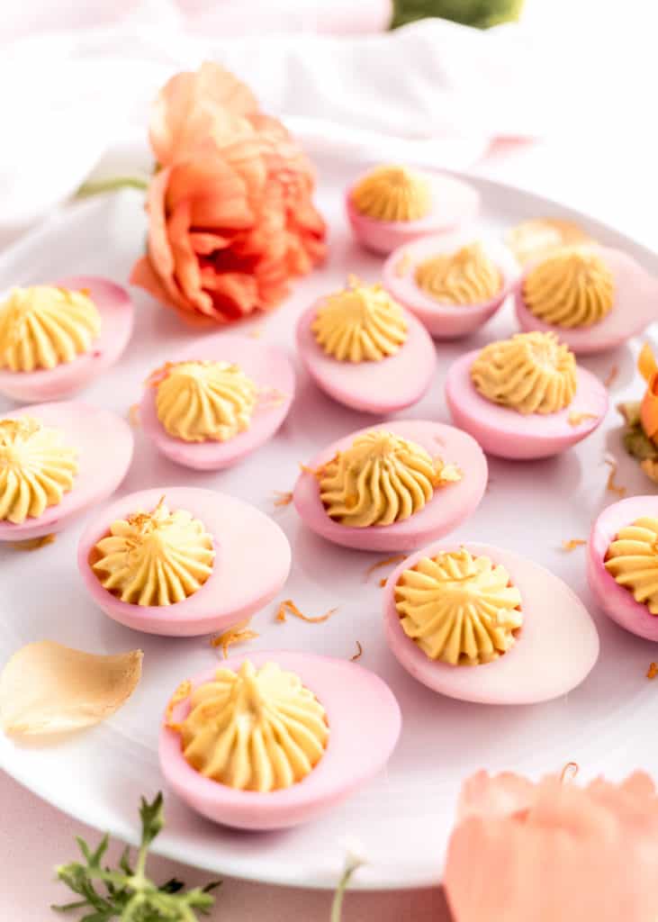 close up shot of pink easter deviled eggs on white platter