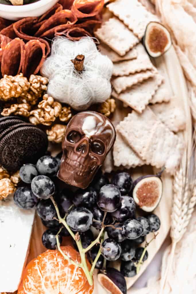 close up of chocolate skull and black grapes on halloween charcuterie board 