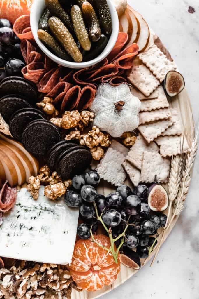 close up of crackers, blue cheese and black grapes on halloween charcuterie board 