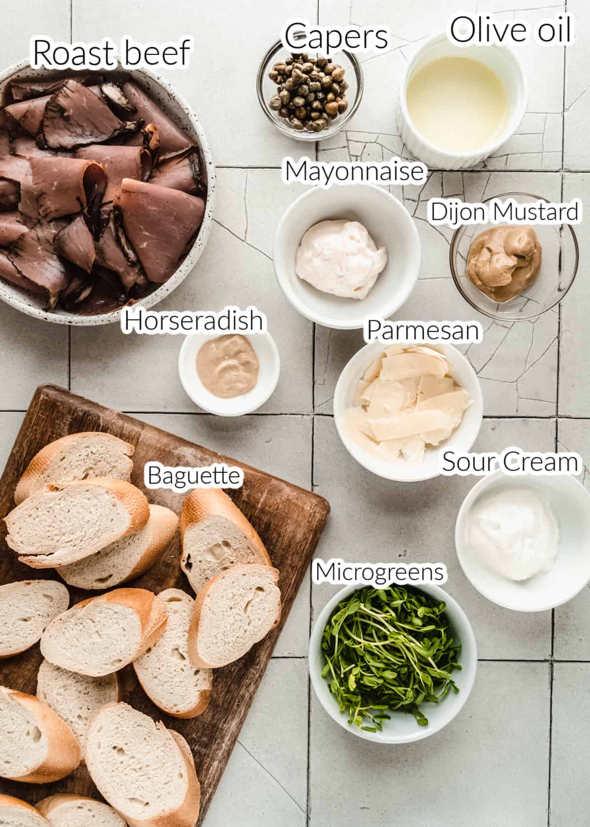 ingredients for roast beef crostini in bowls on tiled surface 