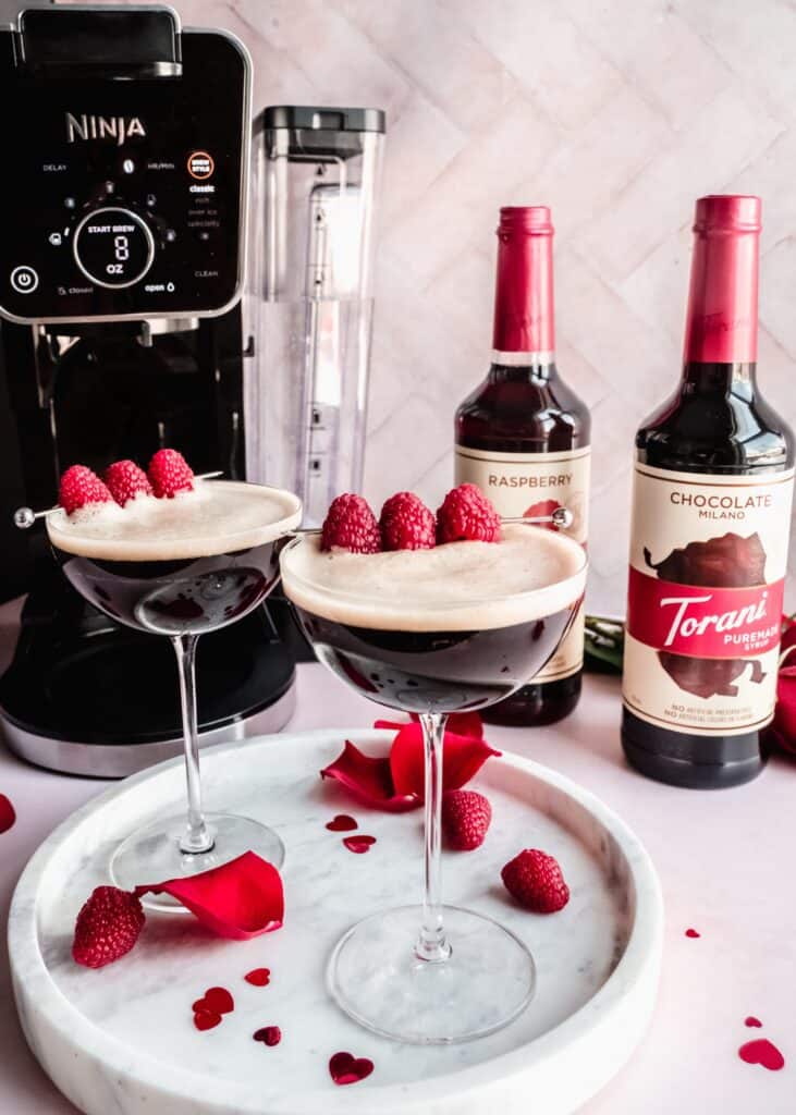 two raspberry chocolate coffee martinis on marble platter with raspberries on platter