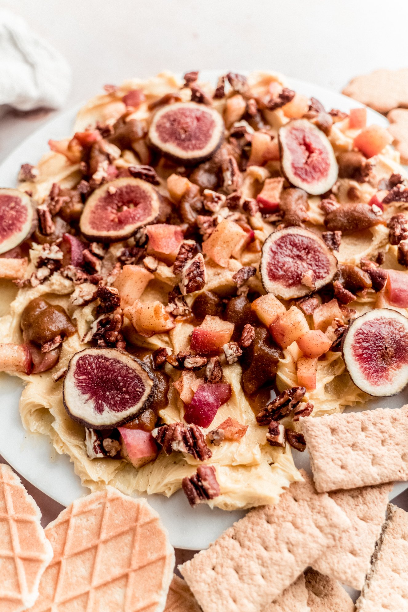 close up of figs and roasted apples on fall butter board on round marble platter surrounded by graham crackers