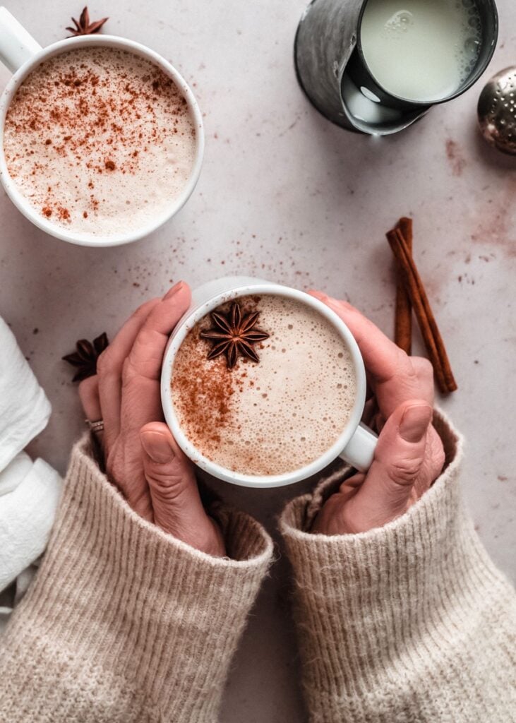 two hands holding spiced rum latte in mug