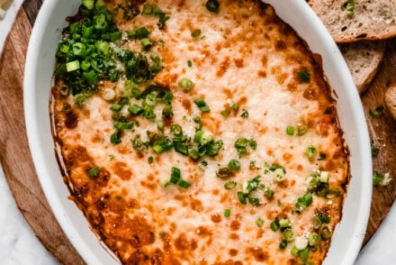 crab rangoon dip in baking dish garnished with chopped green onions