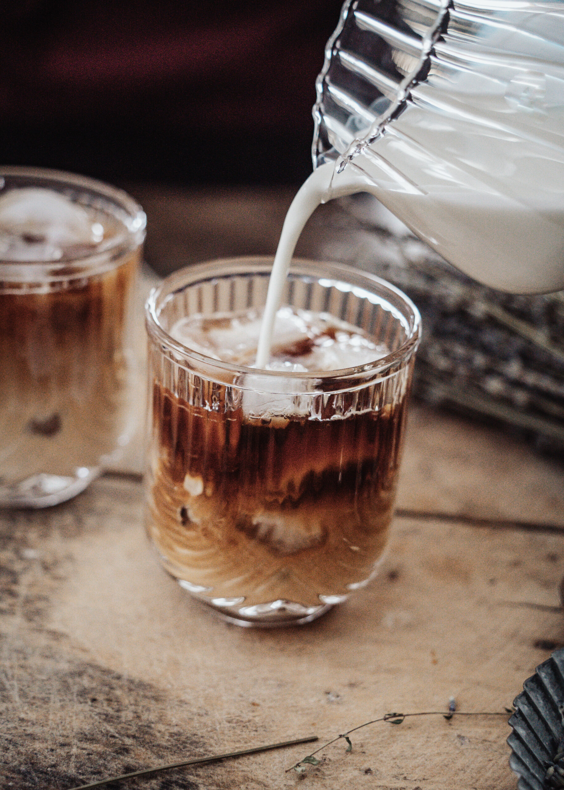 Milk being poured into u shaped glasses with coffee and ice