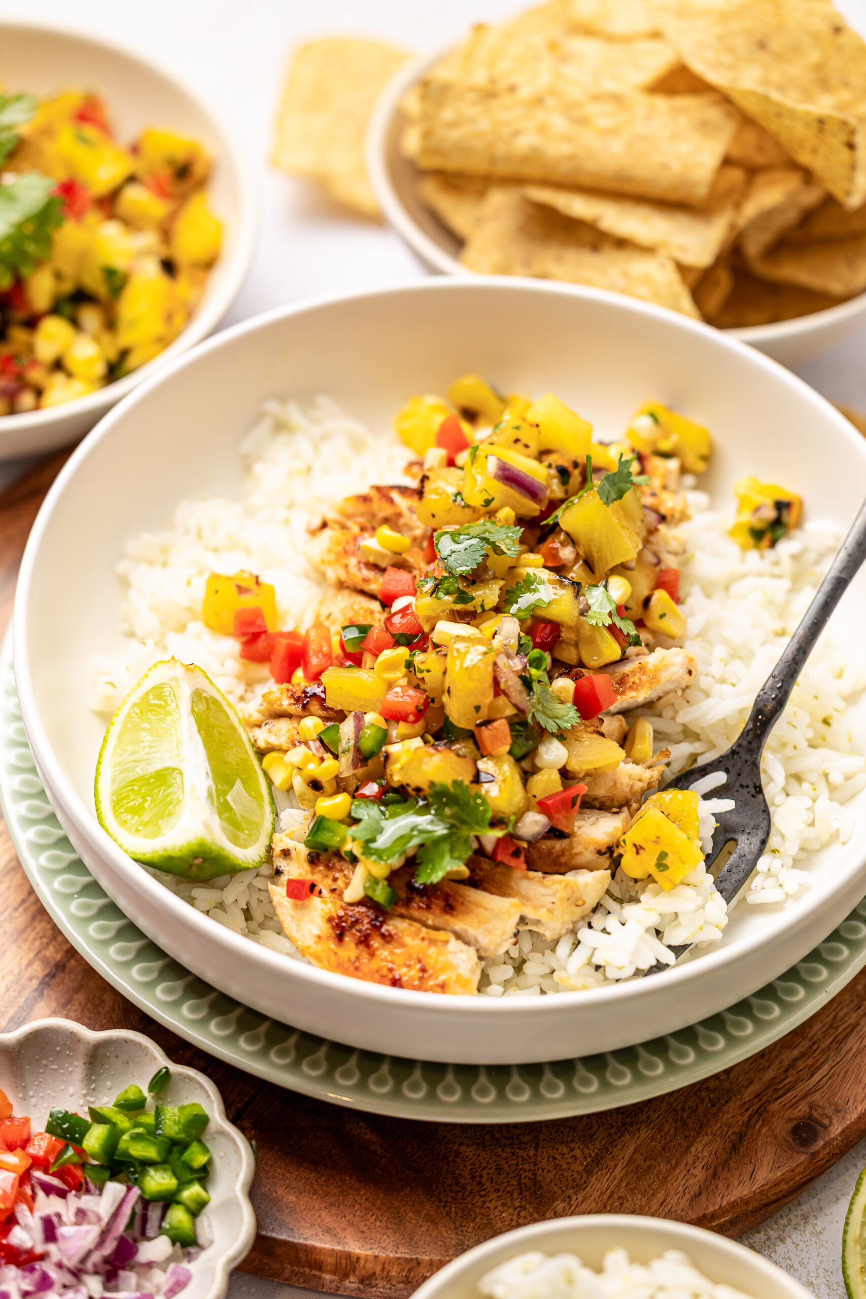 Corn and pineapple salsa in a bowl over white rice.  A bowl of tortilla chips is behind the main bowl.  